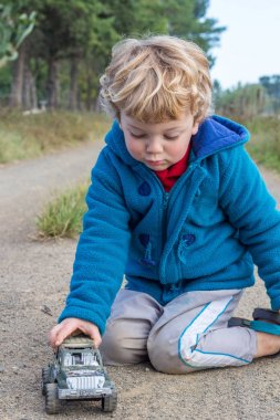Toprak yolda oyuncak araba ile oynarken küçük çiftlik çocuğu