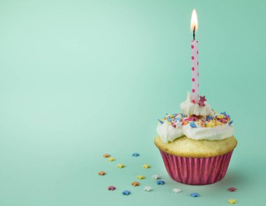 Yanan Mum ve yıldız sprinkles yeşil izole bir cupcake