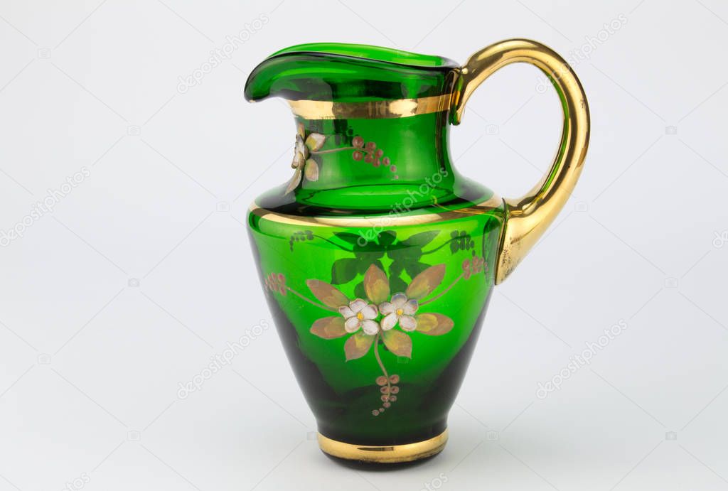 Vintage green and gold glass hand blown milk jug isolated on white background