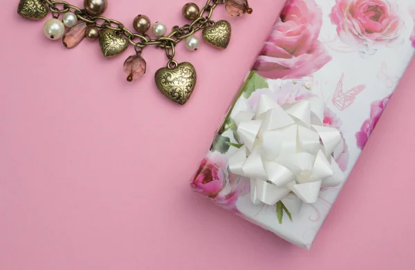 Fundo com coração de ouro e colar de pérolas, envolto presente de rosa — Fotografia de Stock