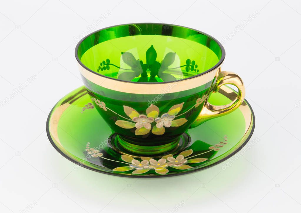 Antique transparent green glass teacup and saucer isolated on white