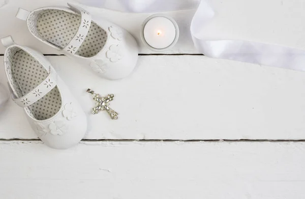 Christening background with white baby booties, crystal cross and candle — Stock Photo, Image