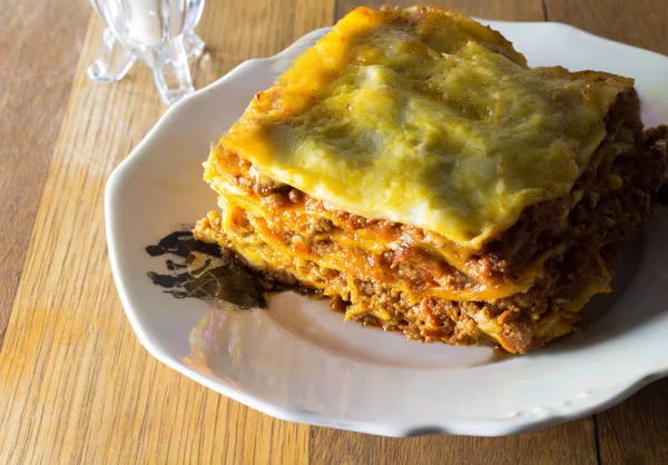 Plaat van één portie pikante rundvlees lasagne voor avondmaal op rustieke tafel met vintage diner plaat — Stockfoto