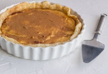 Süt tart ile tarçın baharat serpilir rustik beyaz üzerinde kapat