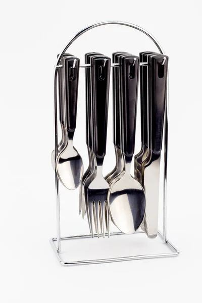 Couteaux, fourchettes et cuillères avec poignées noires suspendues sur étau métallique — Photo