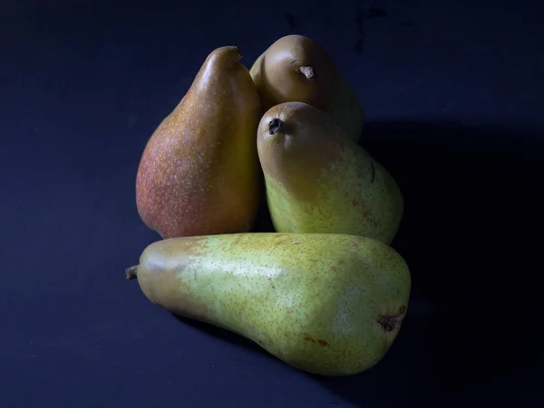 Pear fruit background with four fresh organic pears as unusual still life on dark background — Stock Photo, Image