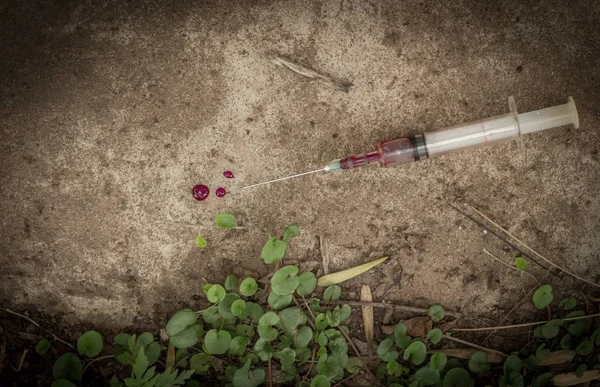 Syringe and needle with blood outdoors on pavement Stock Picture