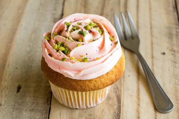 Rosa Tasse Kuchen mit grünen Streusel auf rustikalen Holztisch schließen — Stockfoto