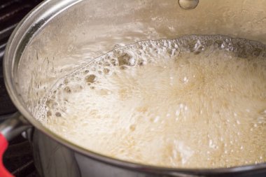 Tencerede kaynama ve köpüren sıvı yakın çekim 