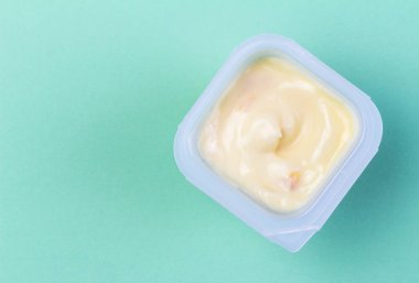 Sağlıklı şeftali - kayısı Meyve aromalı yoğurt plastik bardak yeşil arka plan üzerinde - üstten görünüm izole içinde doğal boyama ile