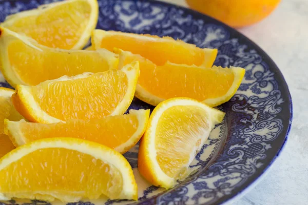 Orange slices close up on blue and white plate - Citrus fruit background