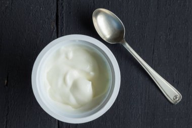 Eski siyah Ahşap mutfak masasında plastik kap içinde Yunan yoğurt