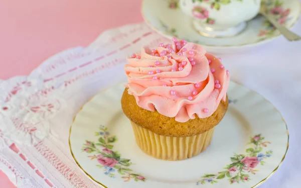 Gâteau glacé rose aux paillettes et perle sur assiette avec tasse à thé — Photo