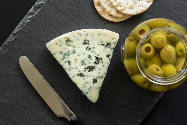 Foto vista superior de queso azul Stilton, tarro de aceitunas rellenas y galletas saladas — Foto de Stock
