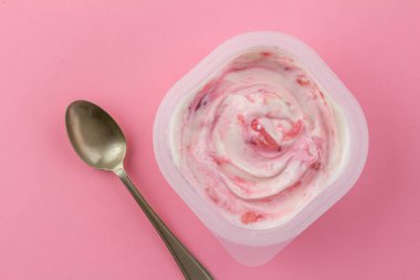 Beyaz plastik bardakta, kaşık izole edilmiş çilekli pembe yoğurt.