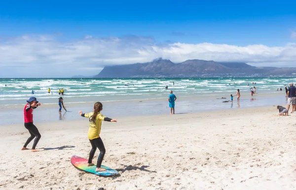 Surfing coach at Muizenberg beach teaching a young girl to surf — 스톡 사진