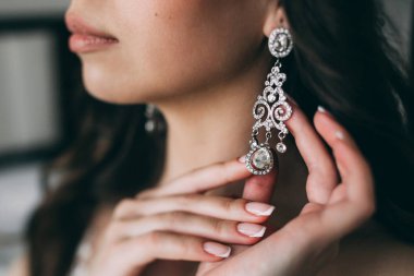 Gelin, küpe, güzel küpeler ve gelinin ellerini düzeltir..