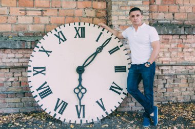 büyük bir saatin yanında bir adam