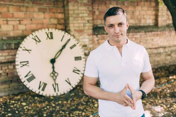 büyük bir saatin yanında bir adam