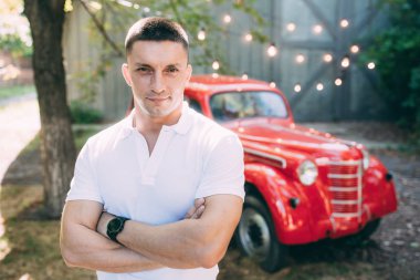 bir adamın yanında eski bir kırmızı araba
