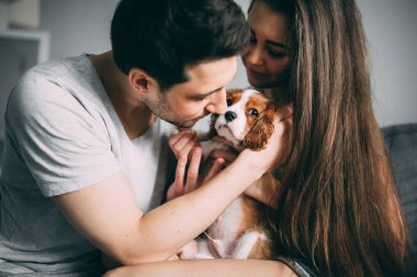 Bir adam ve bir kız rahat bir ev ortamı içinde fotoğraf çekimi. Bir aile üyesi küçük bir köpektir.