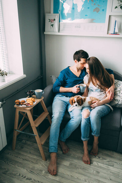 A photo session of a guy and a girl in a cozy home environment. A family member is a little dog.