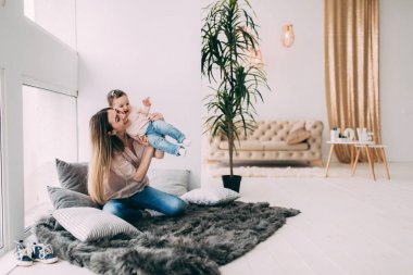 Genç bir annenin kızı rahat bir ev ortamı ile fotoğraf çekimi.