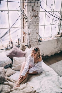 Beyaz bir yatakta bir pencere yakınında bir genç kız.