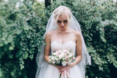 Bir gelin beyaz elbiseli güzel düğün buket tutuyor.