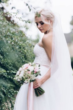 Bir gelin beyaz elbiseli güzel düğün buket tutuyor.