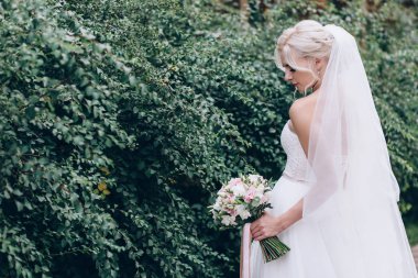 Bir gelin beyaz elbiseli güzel düğün buket tutuyor.