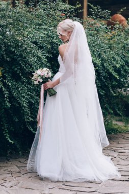 Bir gelin beyaz elbiseli güzel düğün buket tutuyor.