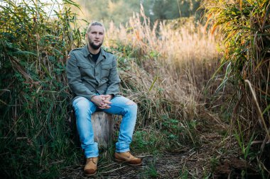 Doğada sakallı genç bir adam portresi.