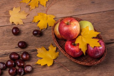 Tahta bir masada elmalar kestaneler ve akçaağaç yaprakları