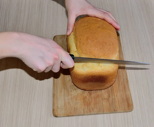 Pão recém-assado é cortado com uma faca — Fotografia de Stock