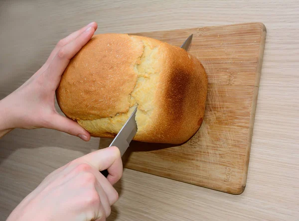 Pão recém-assado é cortado com uma faca — Fotografia de Stock