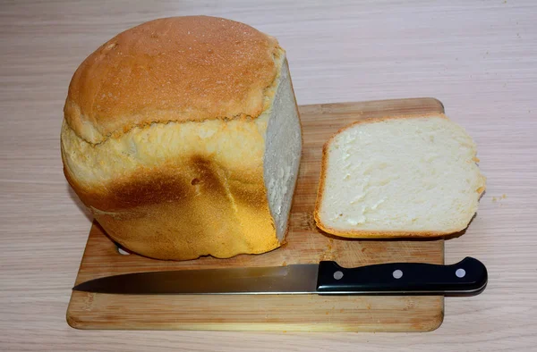 Pão de grão inteiro em uma tábua de pão de madeira esculpida rústica — Fotografia de Stock