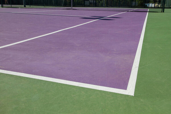 Lines of the corners of a cement tennis court. Track colors are purple and green. 