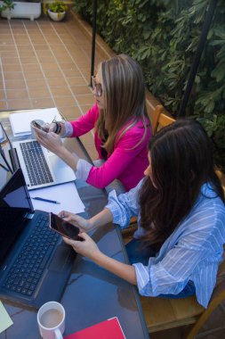 Genç iş kadınları onların laptops ile çalışırken müşteriler cep telefonları ile sohbet. 