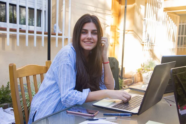 Ung företagsam tjej arbetar med laptop på terrassen i hennes hus. — Stockfoto