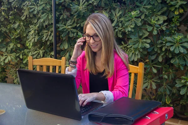 Jeune entrepreneur fille parler sur téléphone mobile tout en travaillant avec ordinateur . — Photo