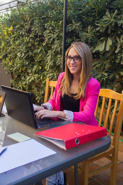 Jeune fille entreprenante travaillant avec ordinateur portable sur la terrasse de sa maison . — Photo