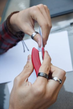 Closeup photo of a person stapling documents with a stapler on a table. clipart