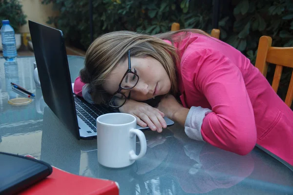 Jeune fille entreprenante fatiguée de travailler autant, elle s'endort sur le dessus de l'ordinateur portable sur la table . — Photo