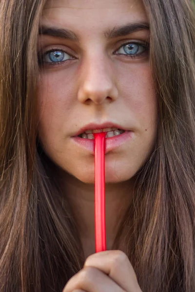 Jong meisje met blauwe ogen en bruin haar rode drop eten. Portretfoto is een close-up van haar gezicht. — Stockfoto
