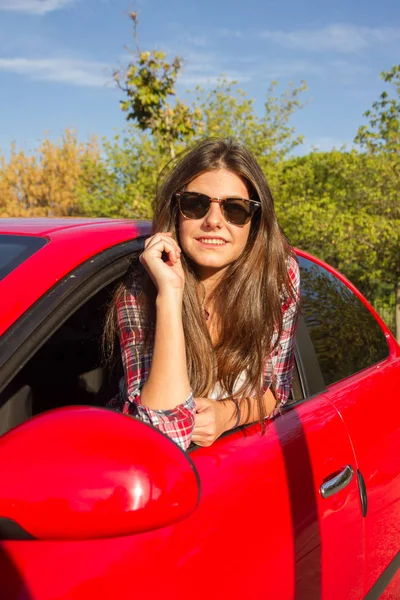 Portret szczęśliwy młoda kobieta jedzie na wycieczkę drogowego pochylony z okna samochodu, czerwony. — Zdjęcie stockowe