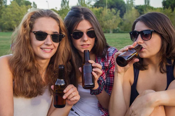 Meninas desfrutando no parque. Eles são amigos comemorando o feriado tendo um bom tempo bebendo cerveja em um parque. Estão felizes. . — Fotografia de Stock