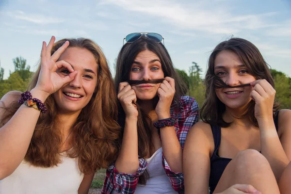 Flickor njuter samtidigt dumt i parken. De gör skämt och grimaser njuta av semester. — Stockfoto