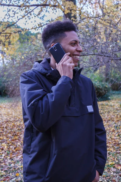 Молодой черный мужчина разговаривает по смартфону в лесу . — стоковое фото