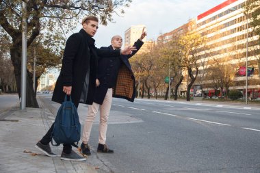 İki genç yakışıklı beyaz işadamları açık şehir, onlardan biri tırnak ve diğer bir taksi için soran kahverengi saçlı.